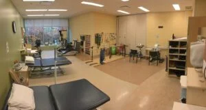 Rehabilitation room with therapy equipment and open floor space.