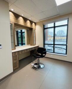 A black salon style chair in from of a brown vanity